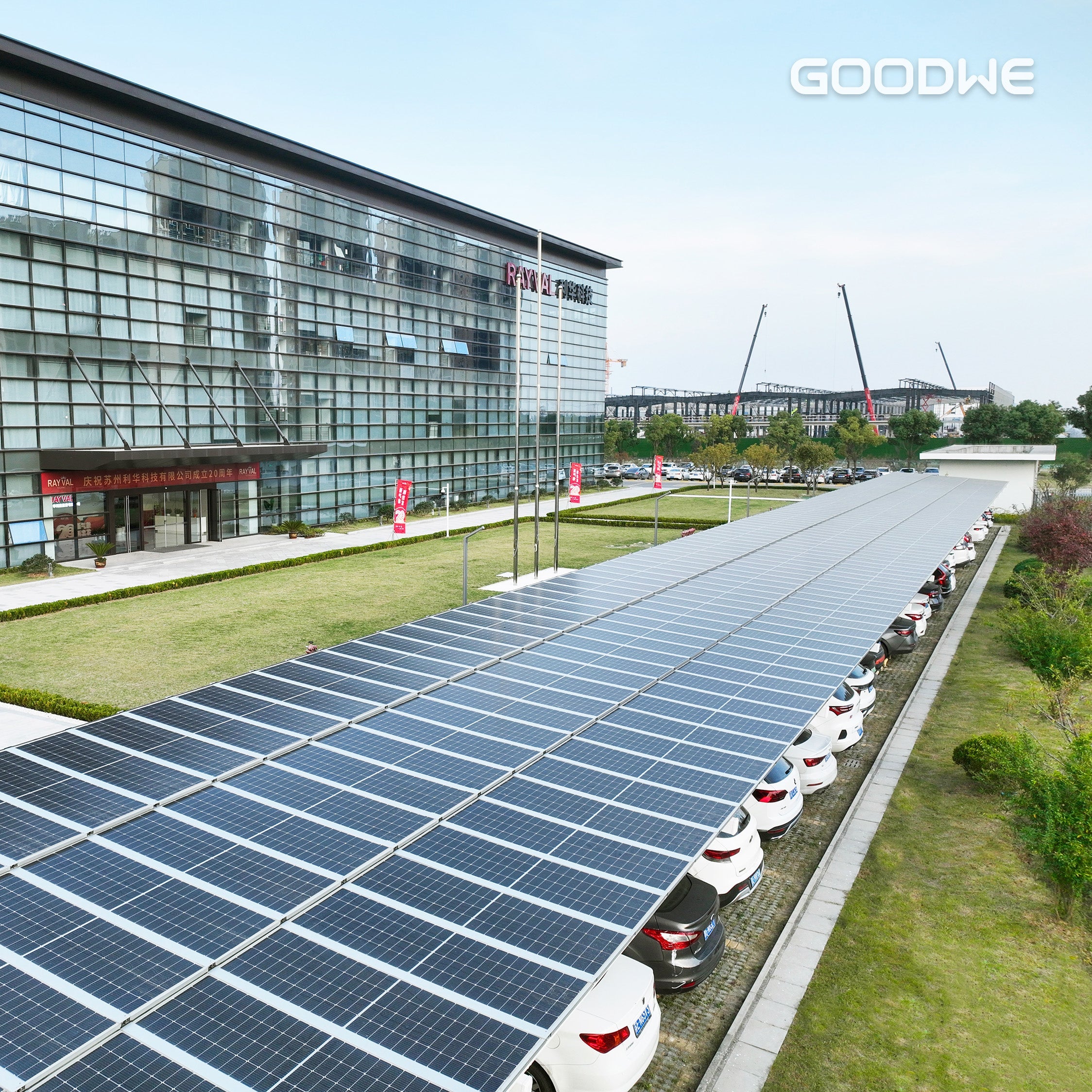 Solar panels lining a road with a modern building in the background, featuring the GOODWE logo.
